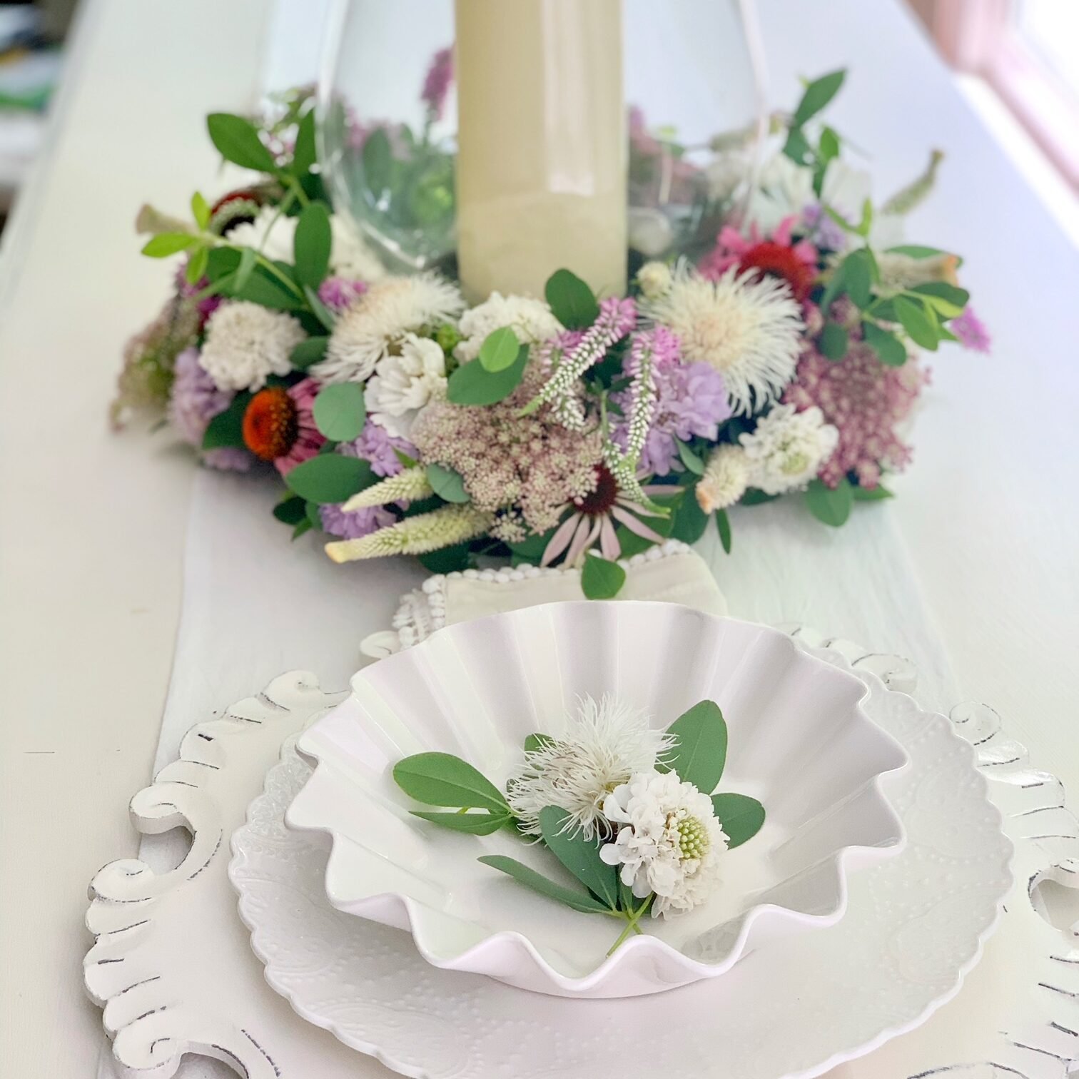 Ring centerpiece on a table setting with white dishes.