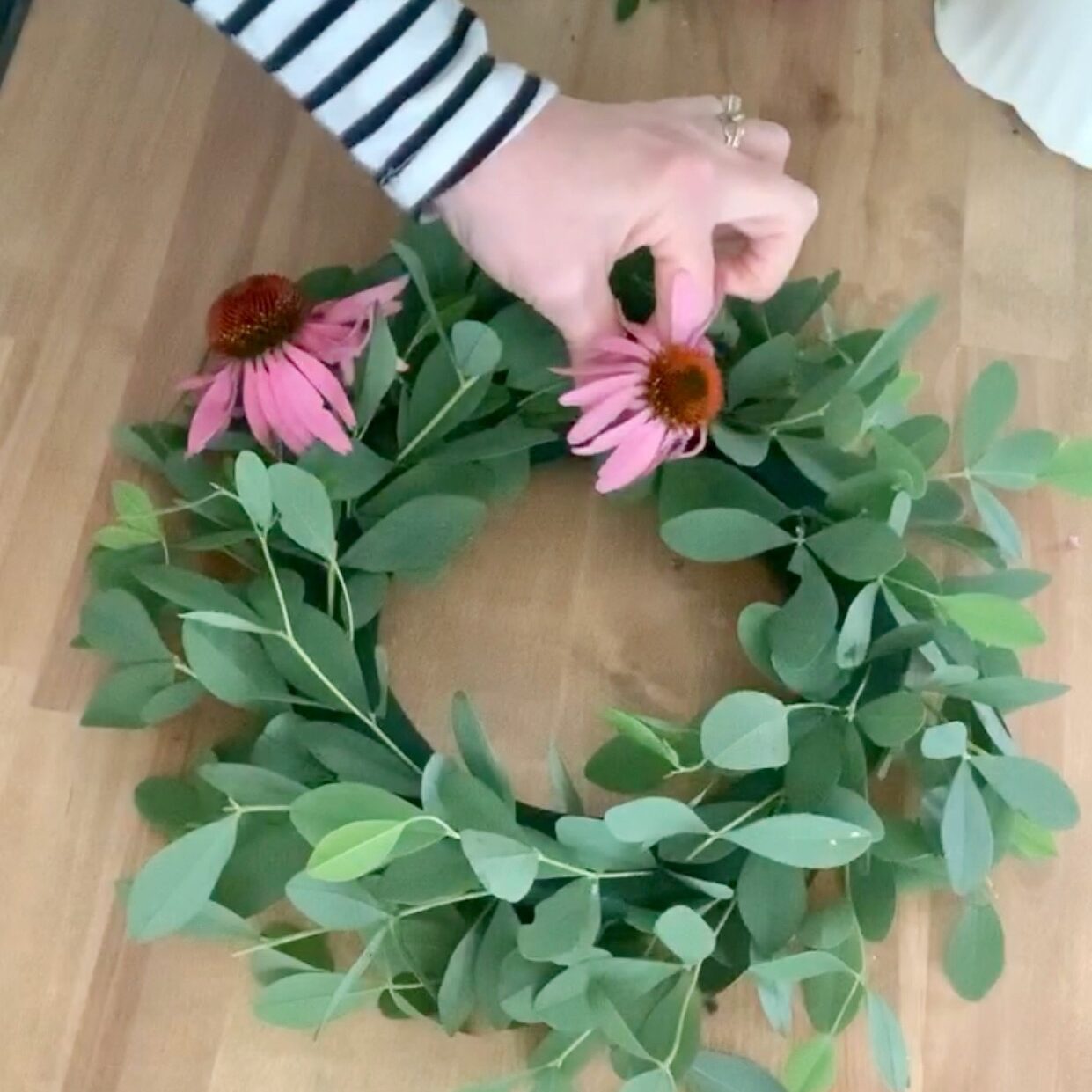 Adding cone flowers to the floral foam ring.