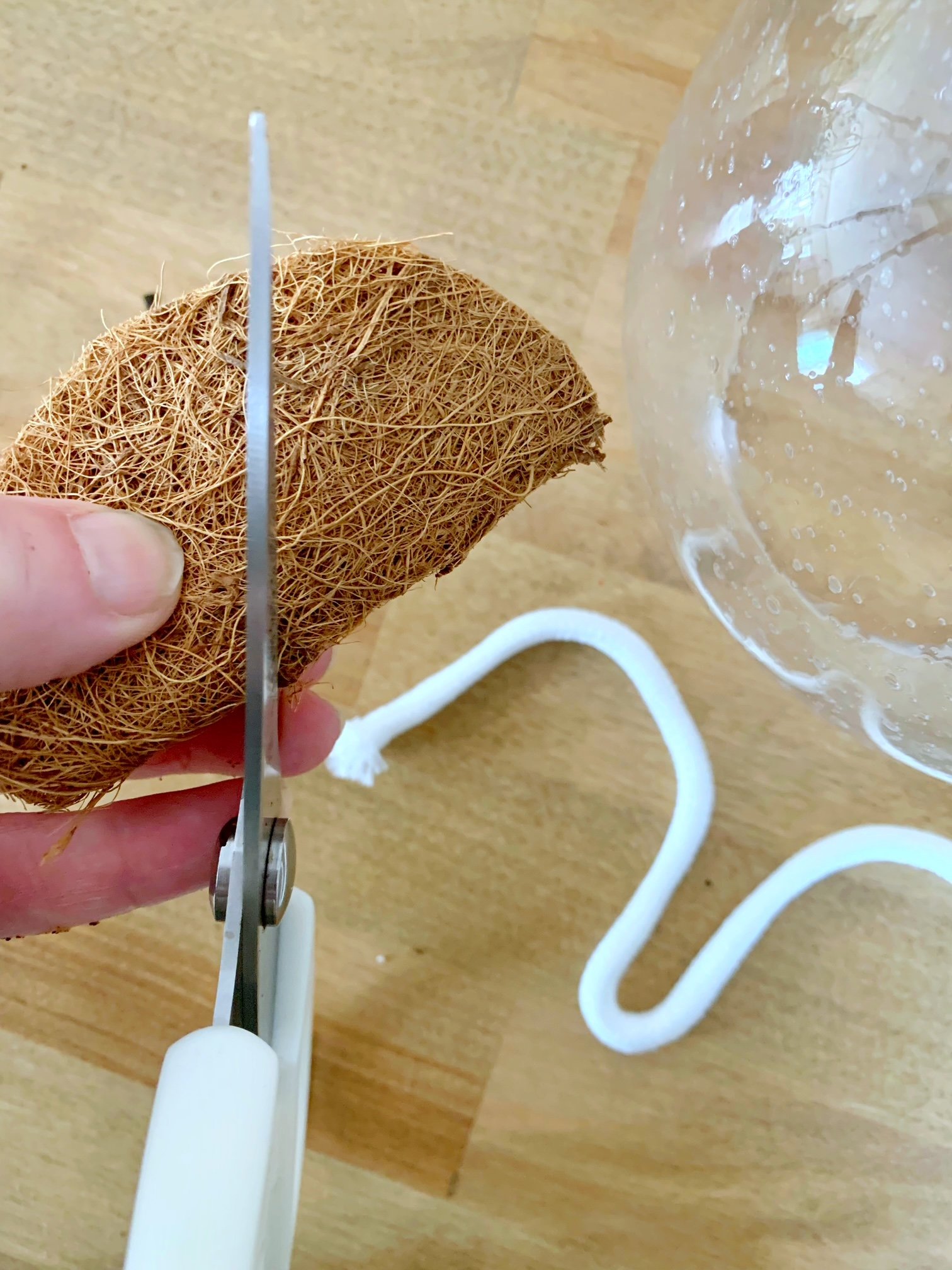 Cutting coconut coir with a hole in the center with the wick.
