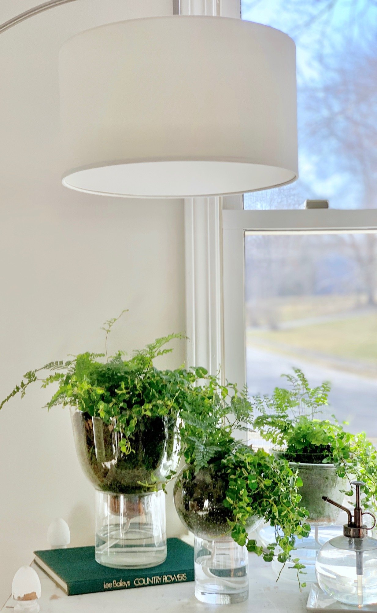 3 diy self watering planters in front of a window with a lamp.