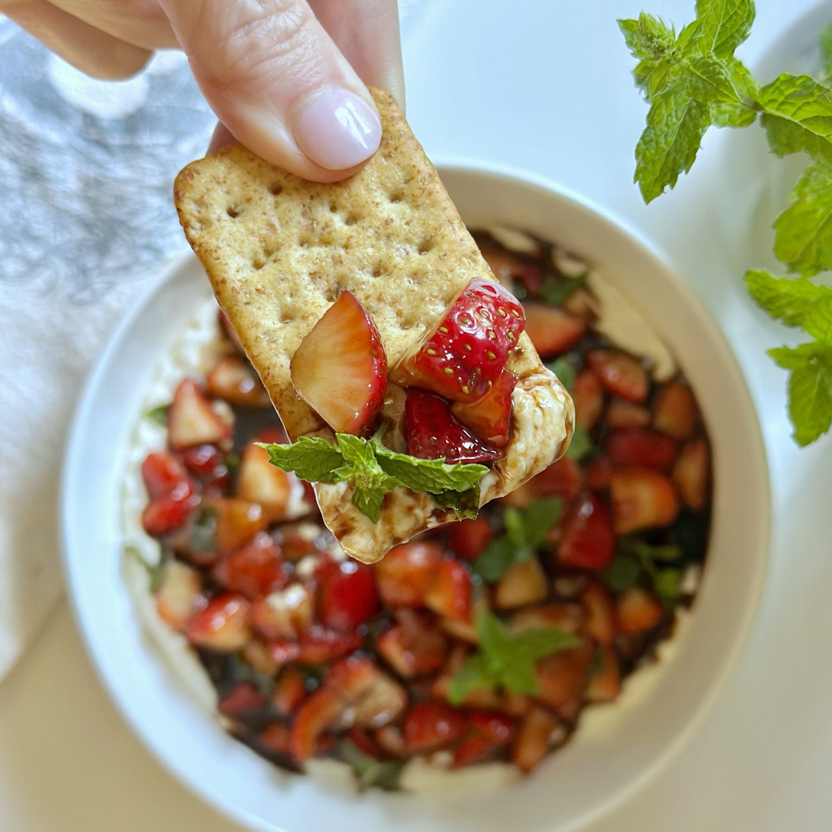 Strawberries cut in small chunk with balsamic vinegar, honey and fresh mint on a cracker.