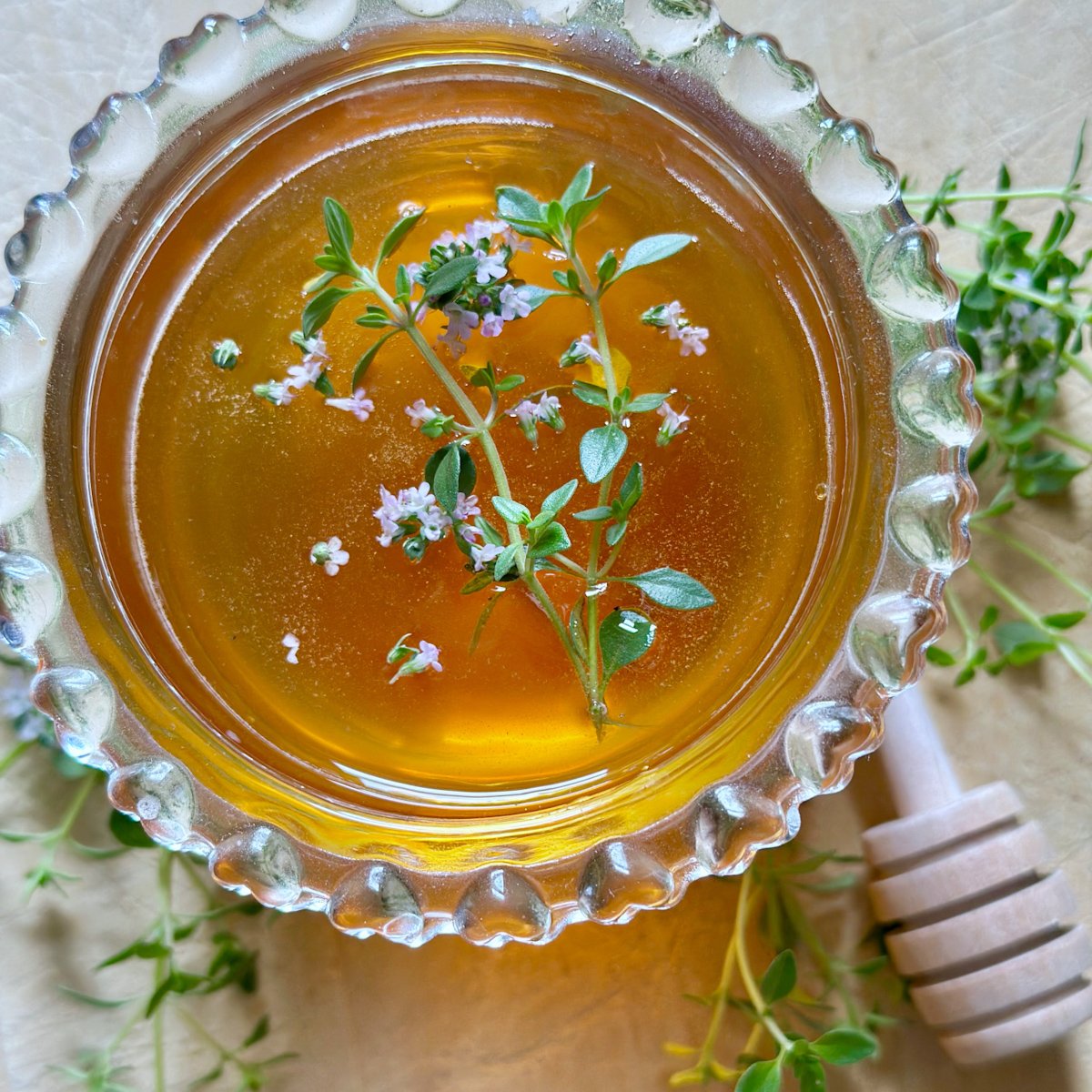 Top view of honey in a clear glass jar with leaves and flowers floating.