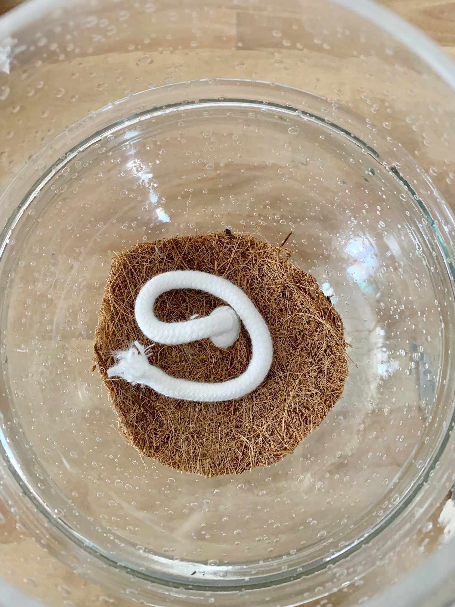 Coconut coir circle with the wick being placed at the opening of the globe.