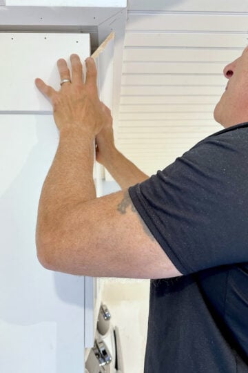 My husband putting crown molding to finish off our DIY beadboard ceiling project.