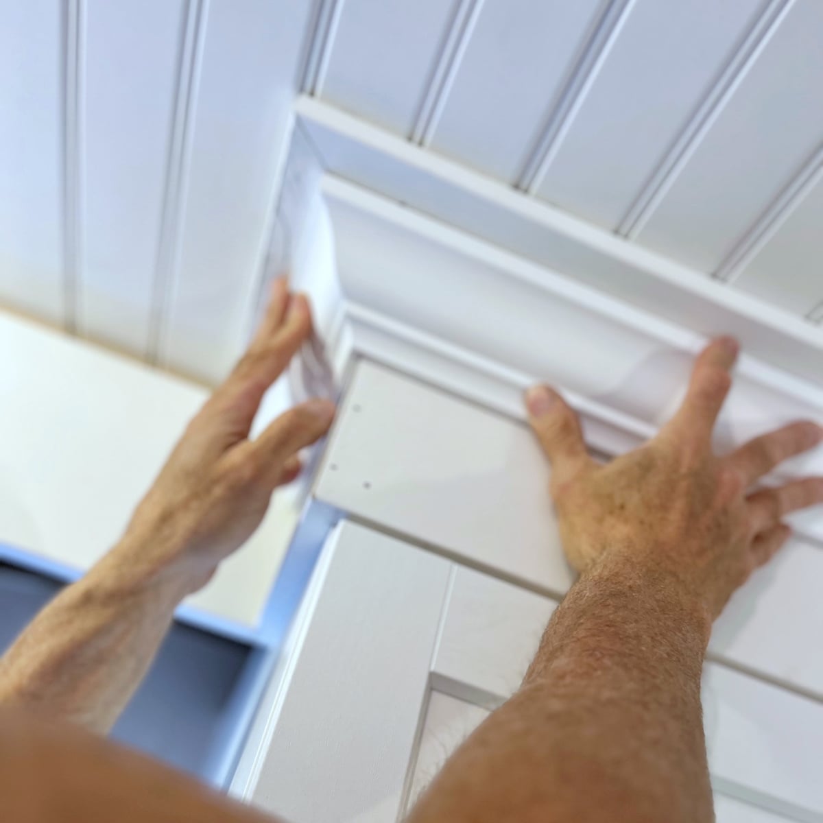 Hands holding up crown molding. 