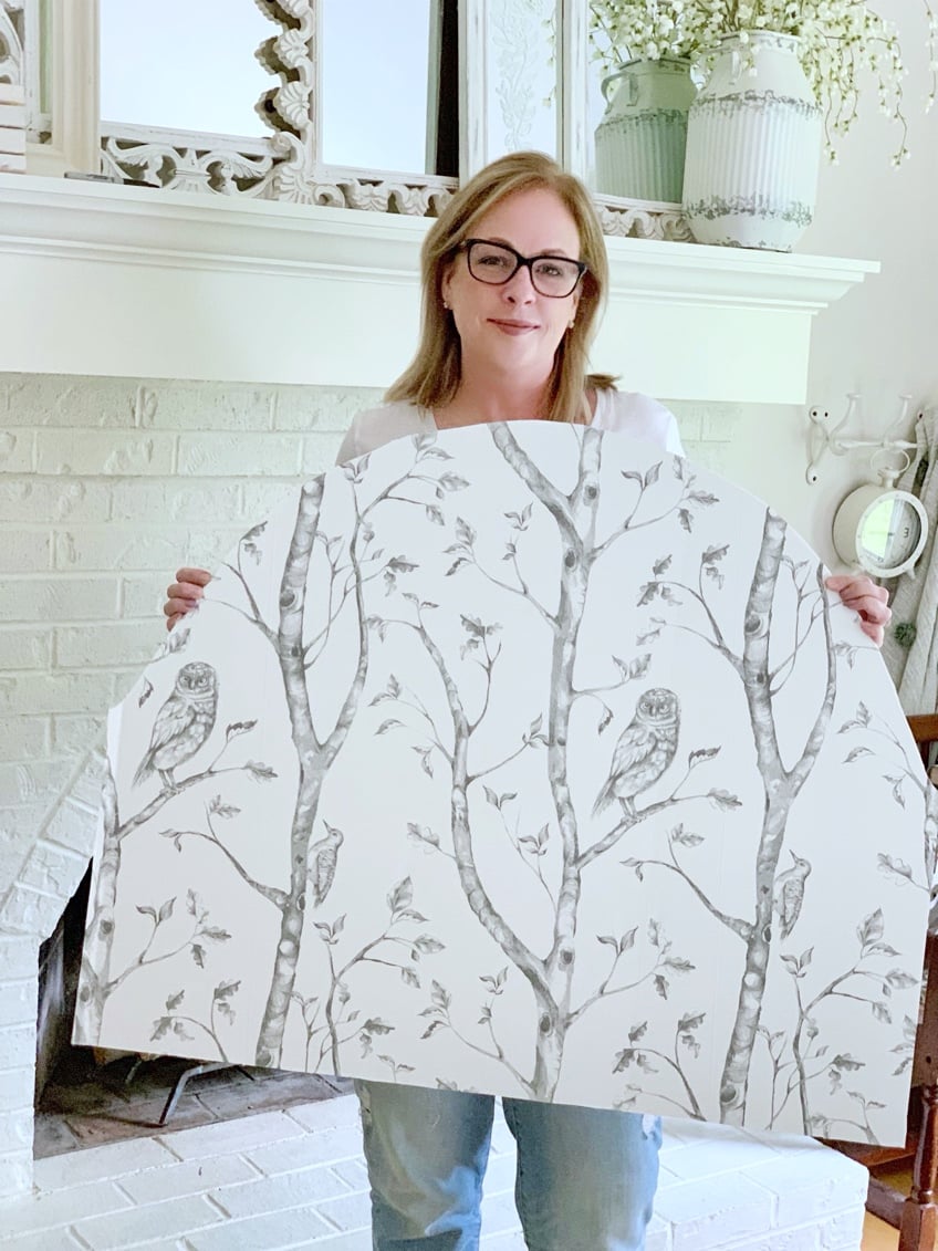 Me holding the cover board with the peel and stick wallpaper on it. 