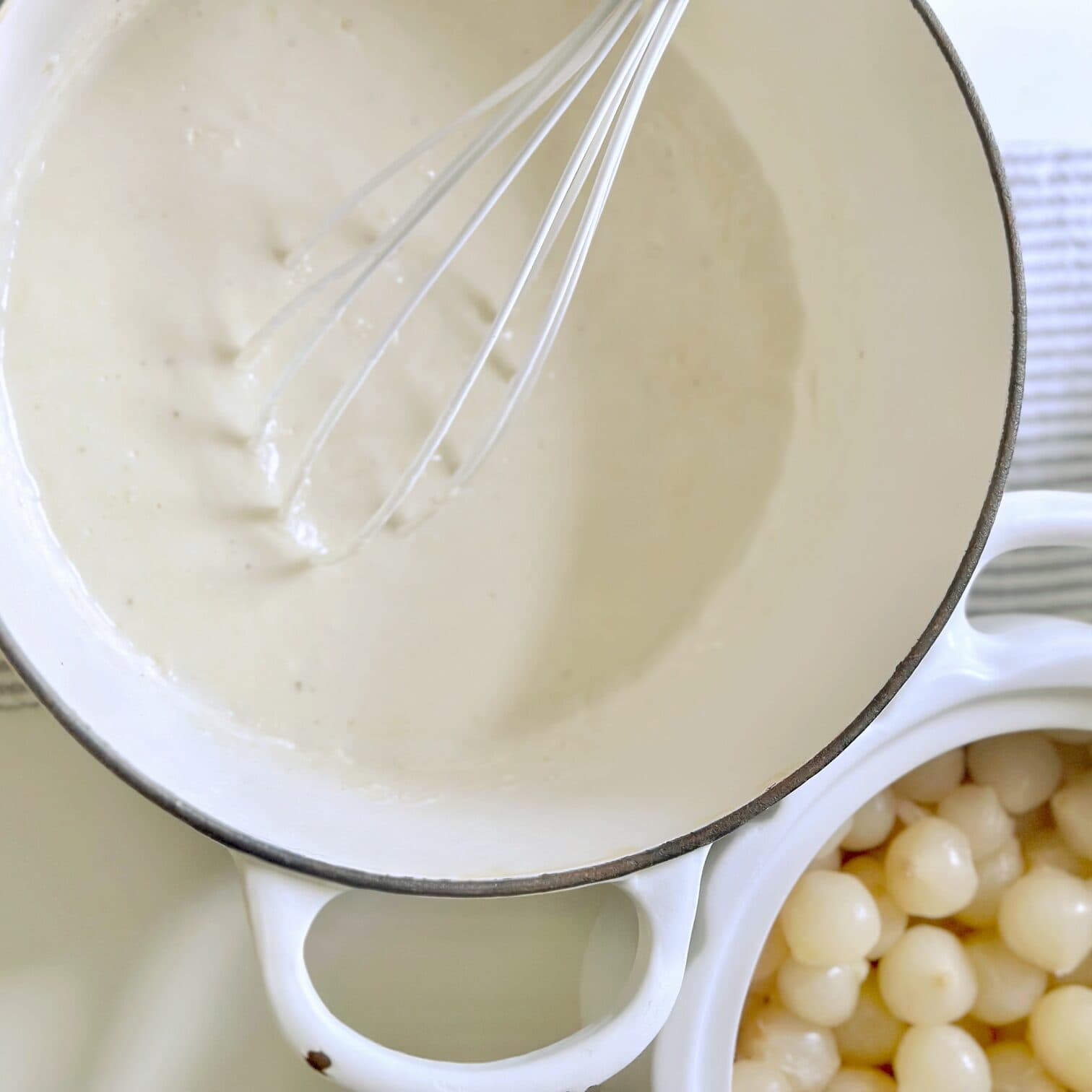 A white pan containing the cream for the onions. 