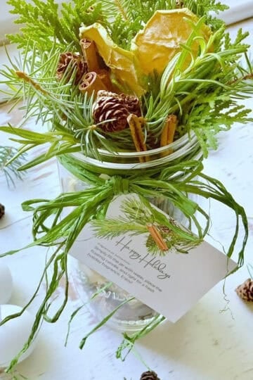 A jar filled with seasonal greens and herbs with candles.