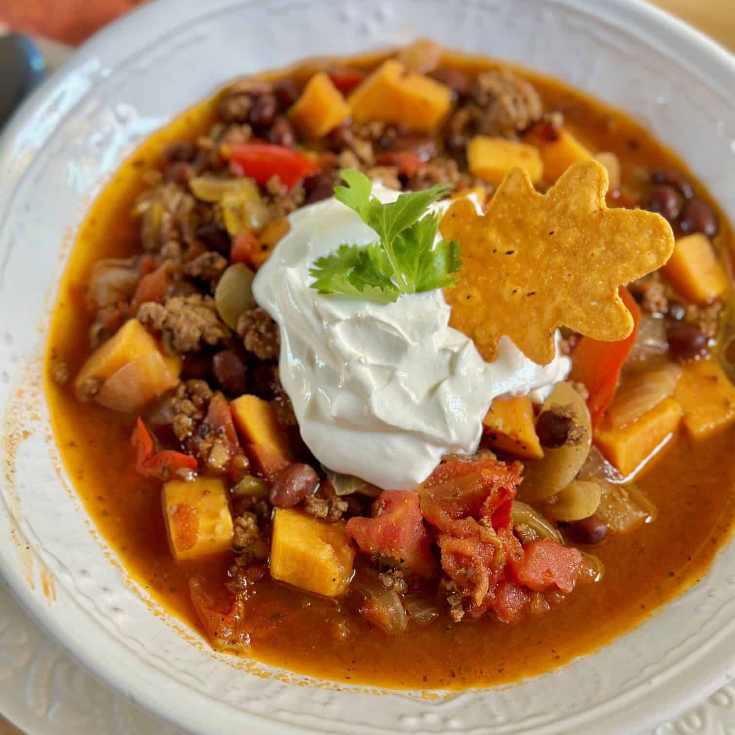 A big bowl of beef sweet potato chili with sour cream and cilantro. 