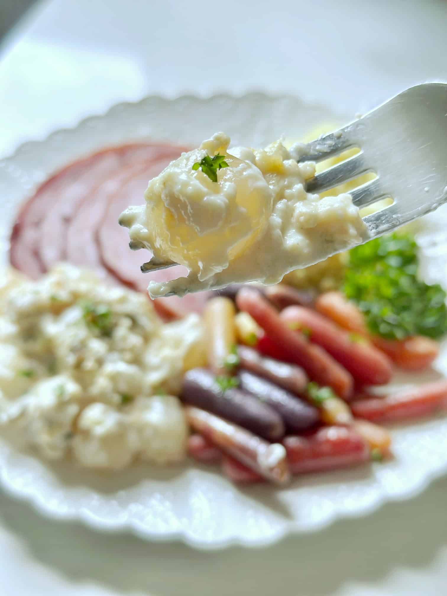 A white plate with creamed onions, ham, cinnamon carrots and rice. 