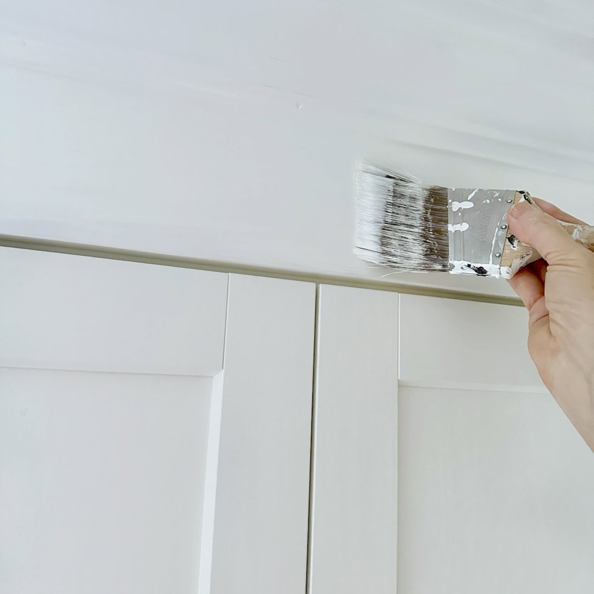 Painting the added trim to our IKEA cabinets white.