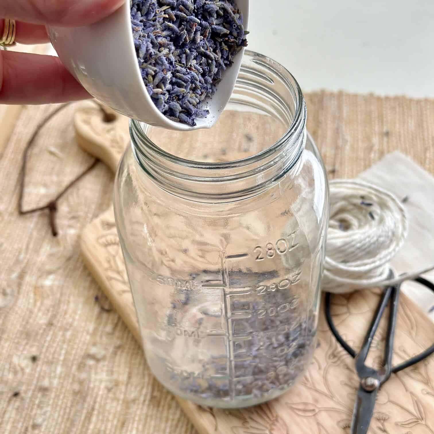 Pouring lavender buds into a clean glass jar. 