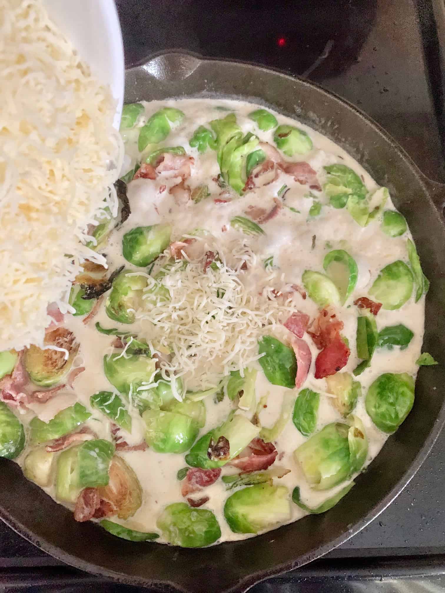 Adding shredded cheese to the mixture. 