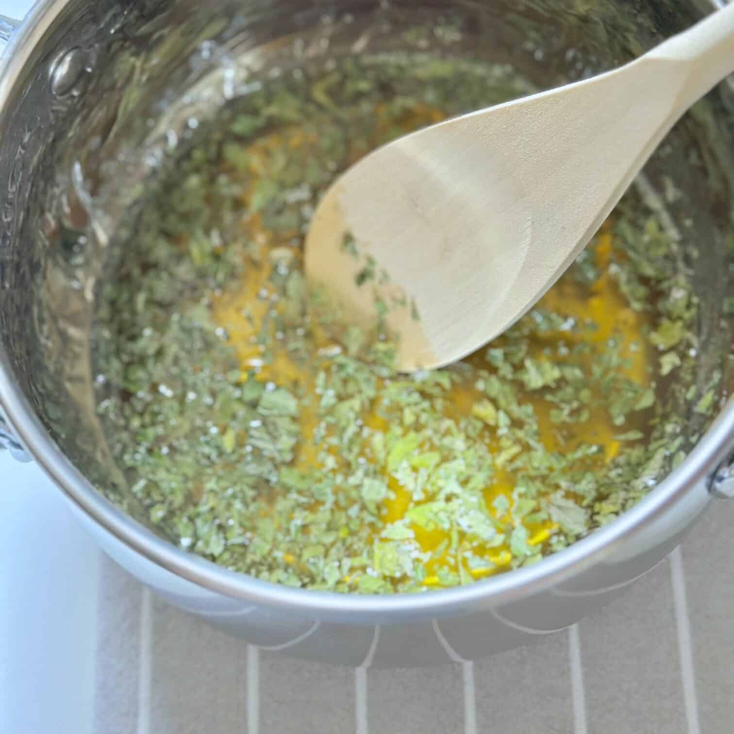 Steeping the honey with dried spearmint in a pot. 