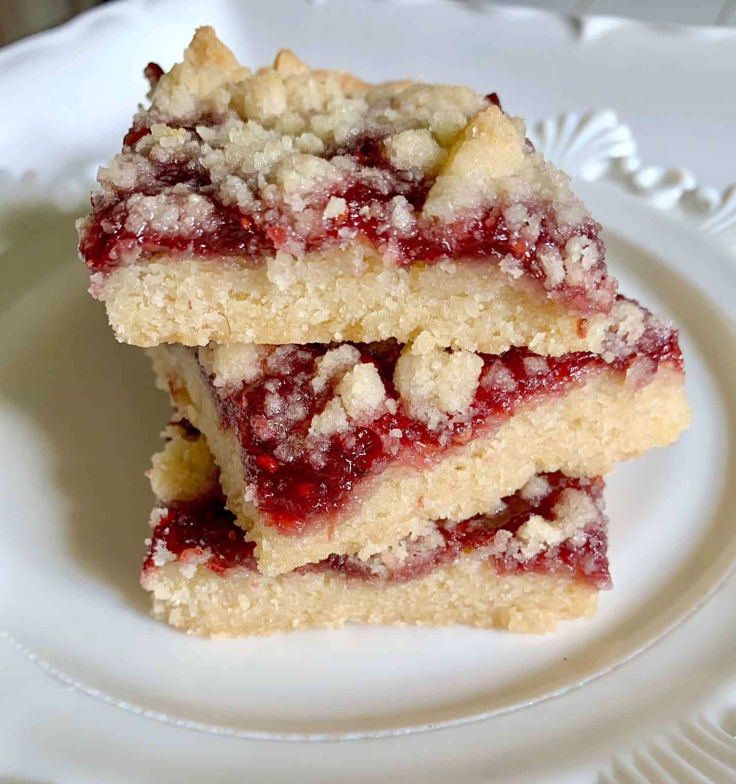 A yummy stack of three raspberry crumb bars on a plate. 
