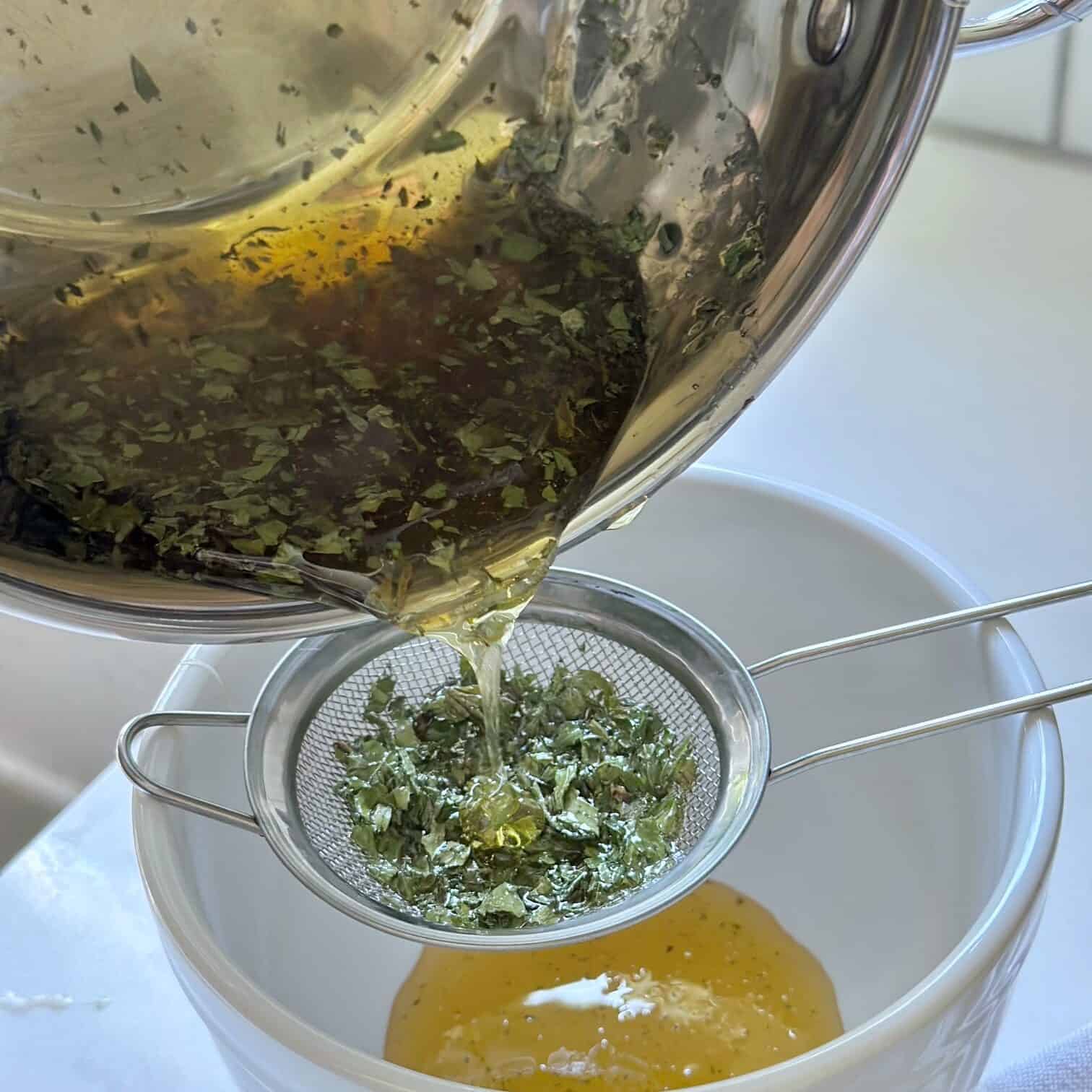 Pouring the honey a mint through a small strainer. 