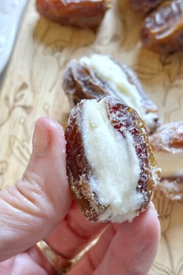 Me holding a stuffed date filled with cream cheese and rolled in sugar.