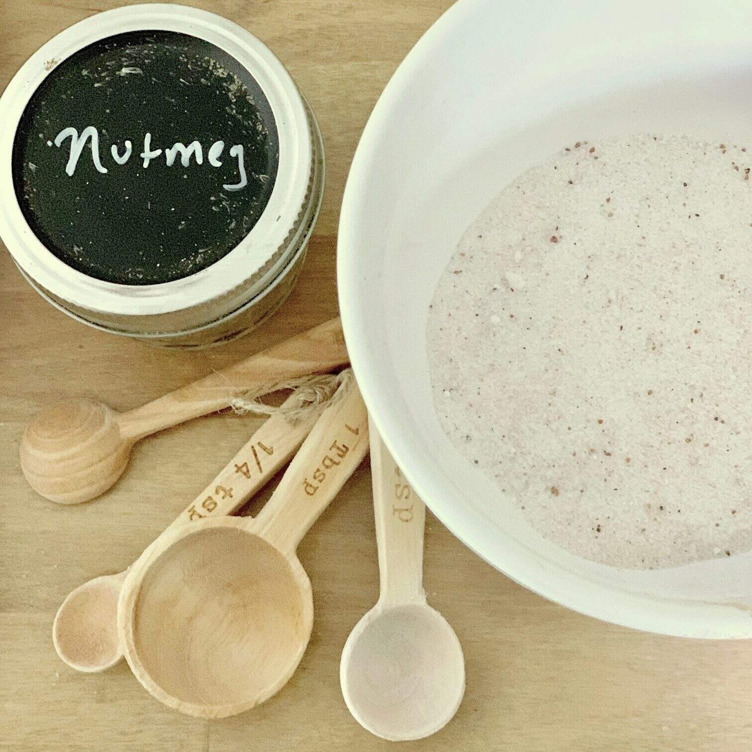 Nutmeg, measuring spoons and a bowl of sugar. 