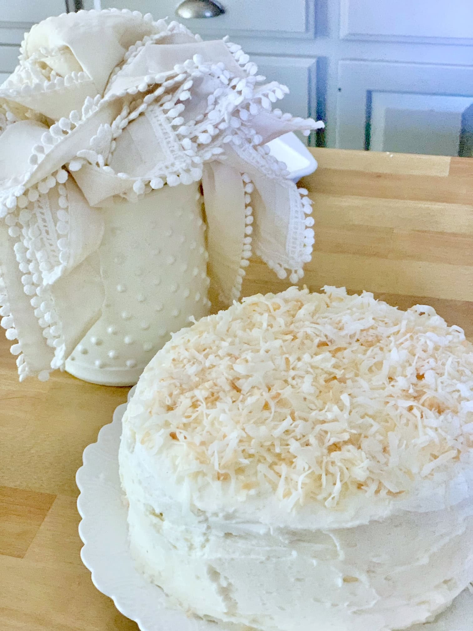 A cake with easy toasted coconut on it with linen napkins in the background. 