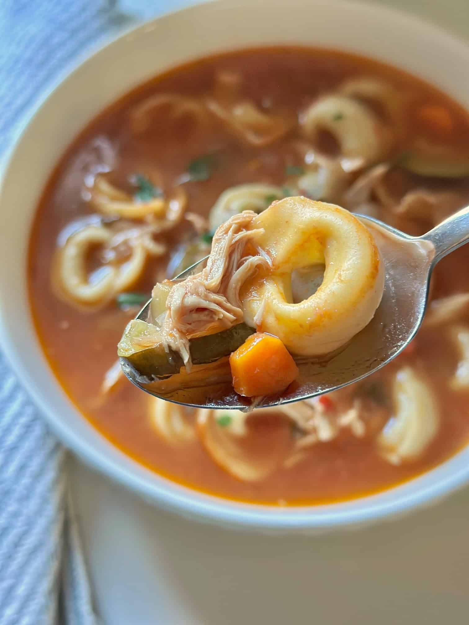 A spoonful of Italian chicken tortellini soup. 