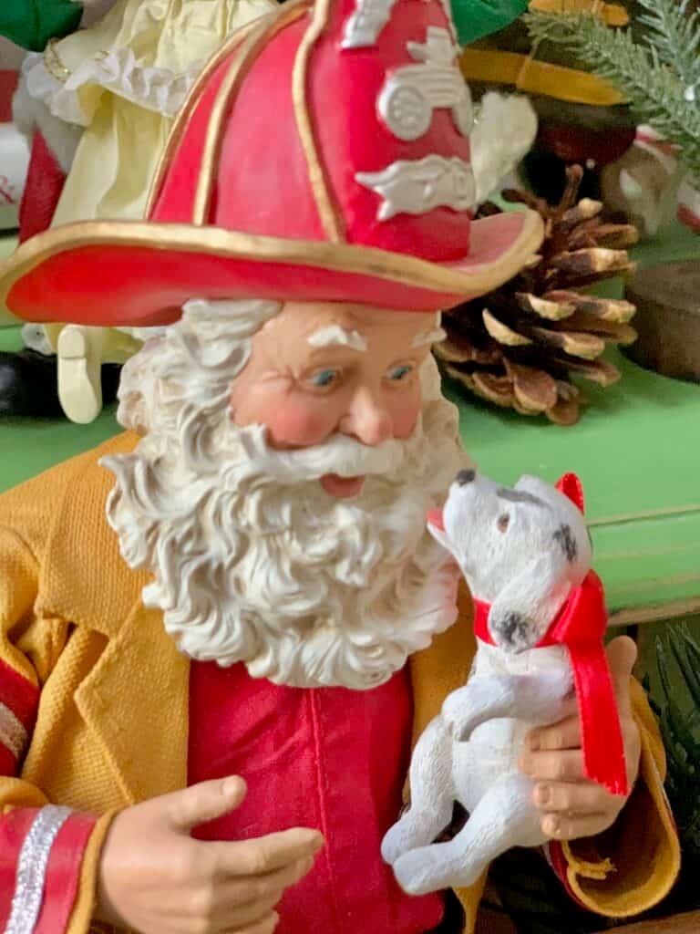 Firefighter Santa figurine in festive holiday setting.