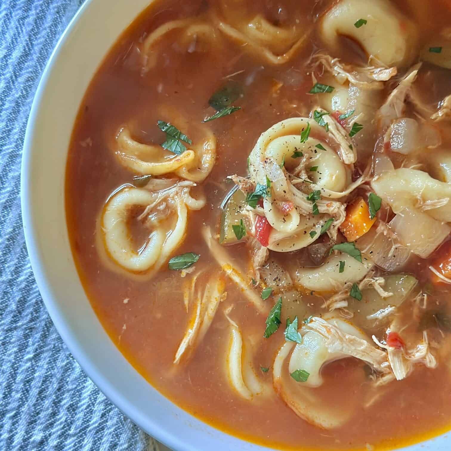 The completed recipe. this Italian chicken tortellini soup is bright and colorful with garnish on top. 