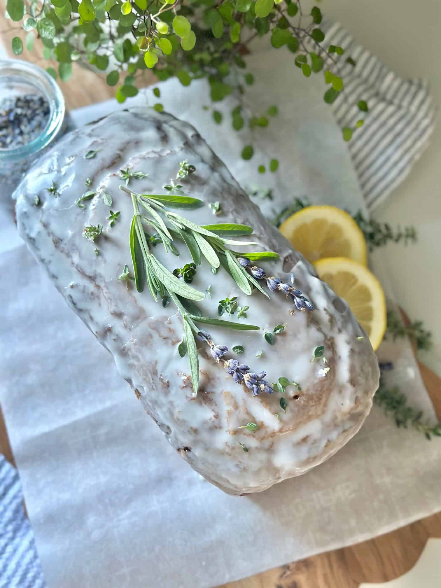 A stunning loaf of lemon lavender pound cake with icing. There are lemon slices and stems of lavender across the top.
