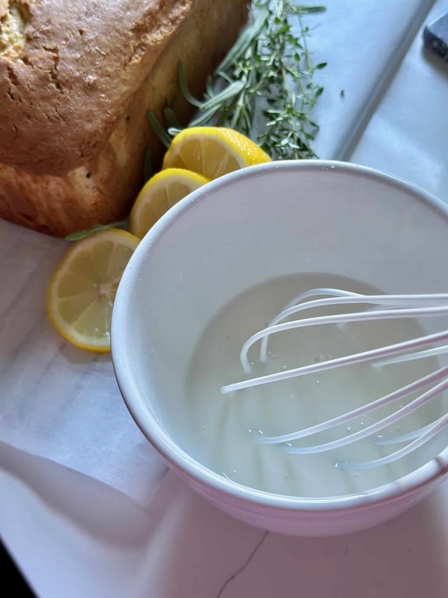 White glaze being mixed in a bowl with a whisk.