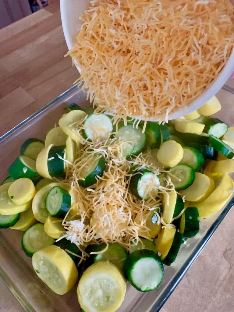 Sprinkling shredded cheese on hot steamed squash. 