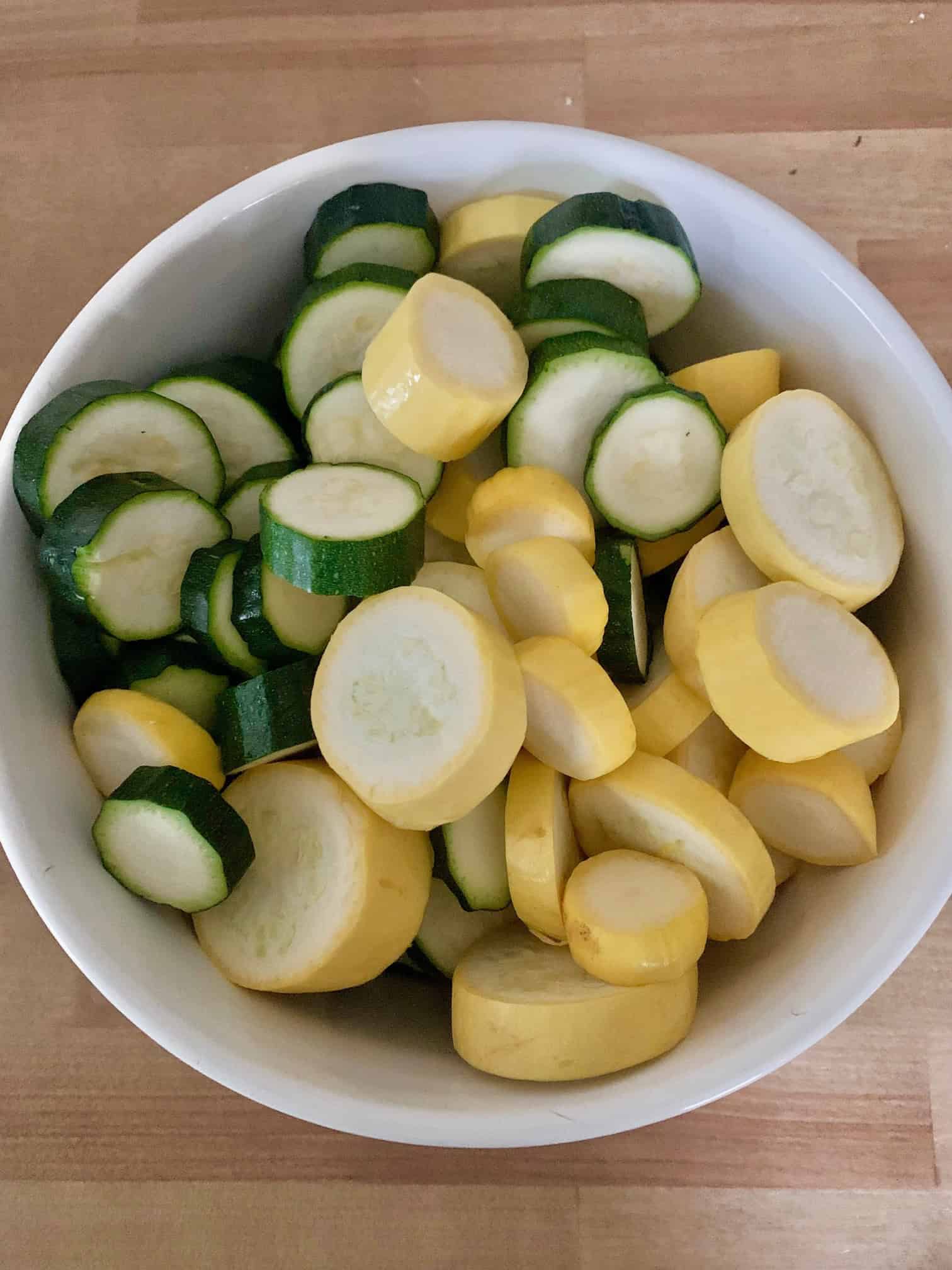 A large bowl filled with zucchini and yellow squash chopped. 