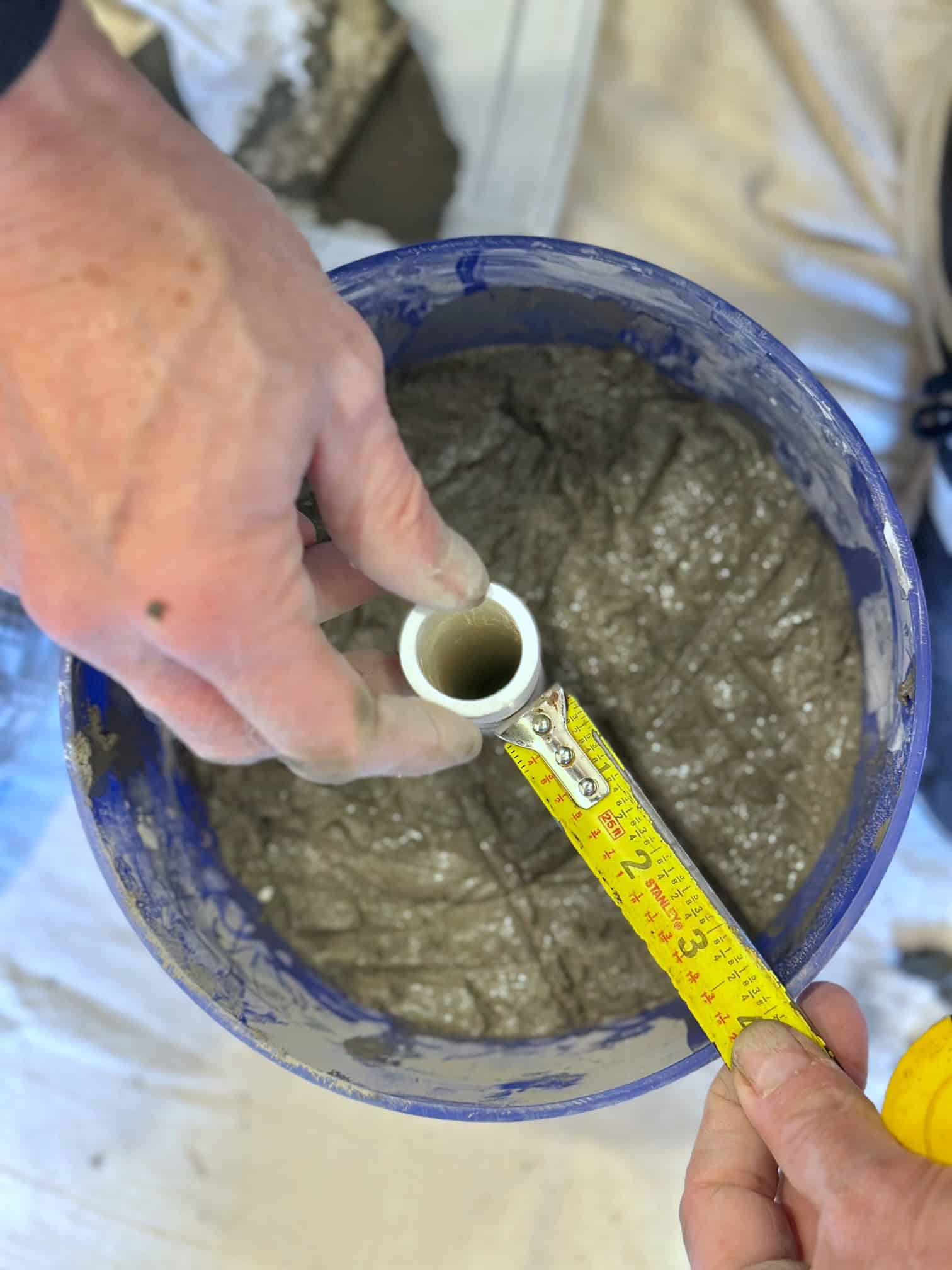 Measuring the PVC pipe in the cement to make sure its centered. 