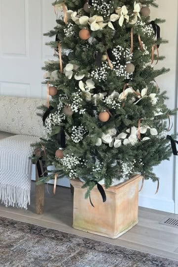 A Christmas tree decorated in a designer-looking tree base.