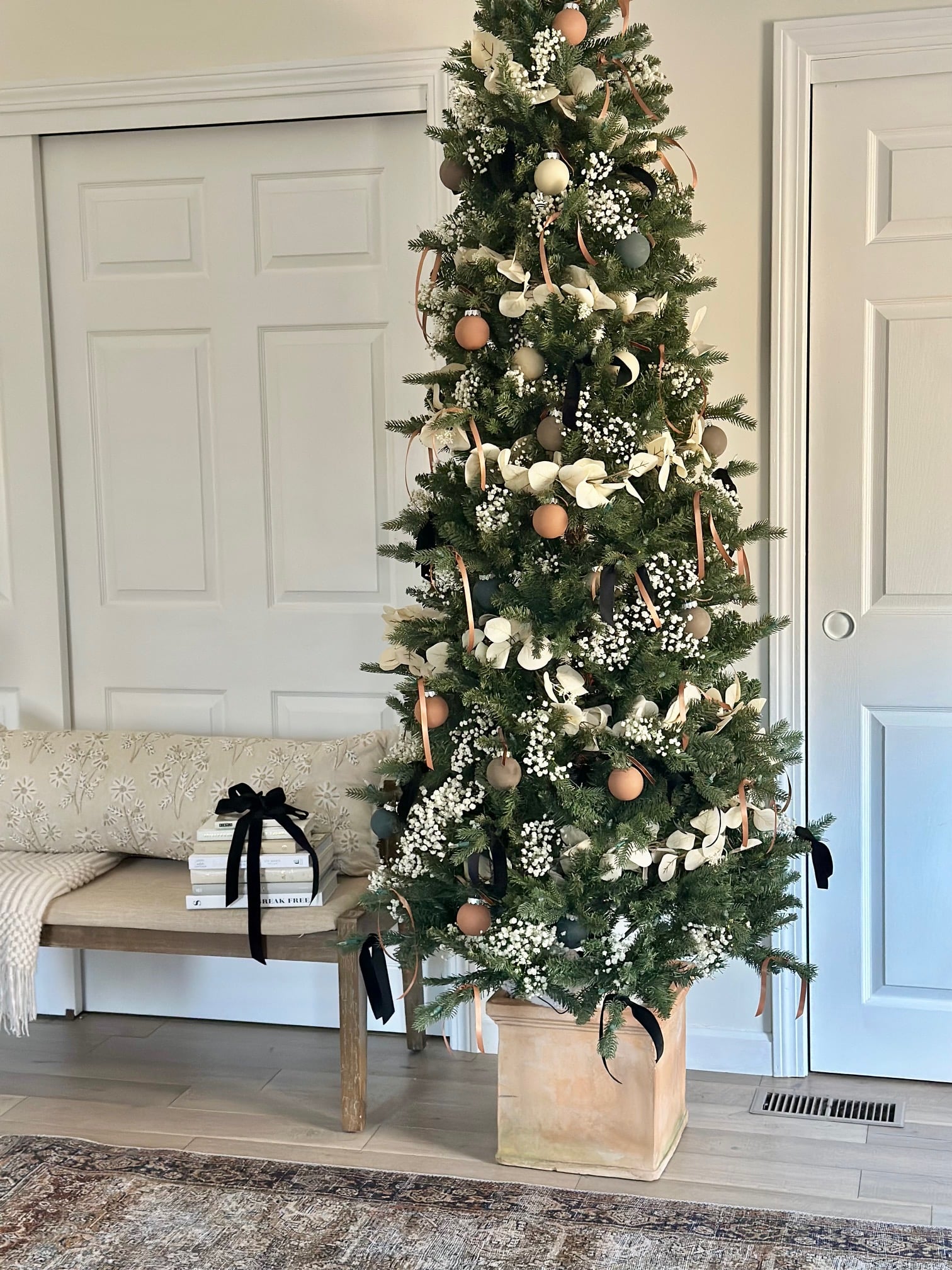 An artificial Christmas tree in a clay square planter.
