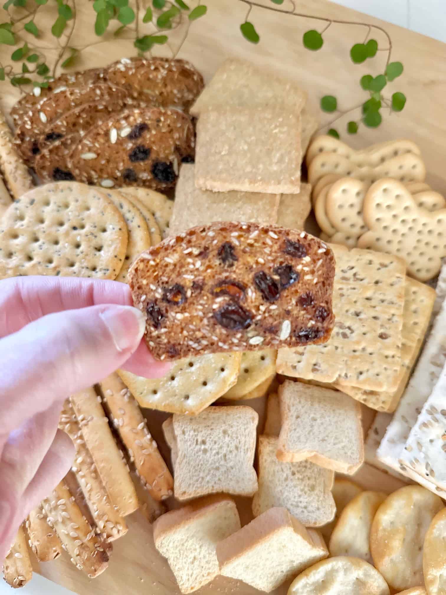 A large assortment of different crackers on a charcuterie board. 