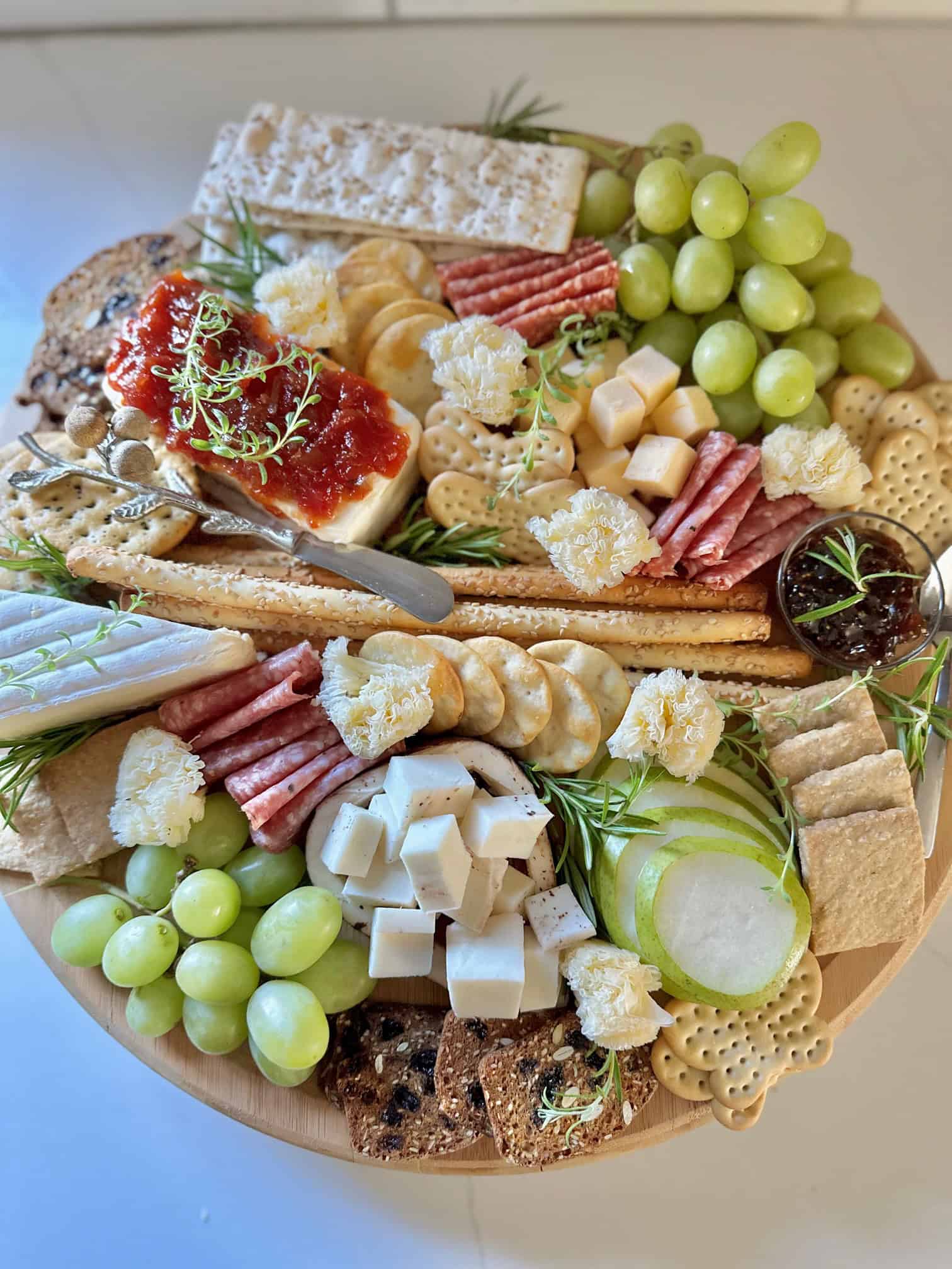 A full charcuterie board featuring cream cheese pepper jelly spread. 
