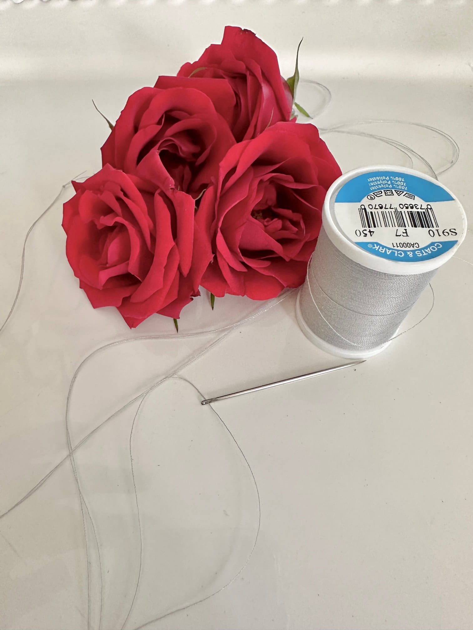 Cluster of red rose heads and thread.