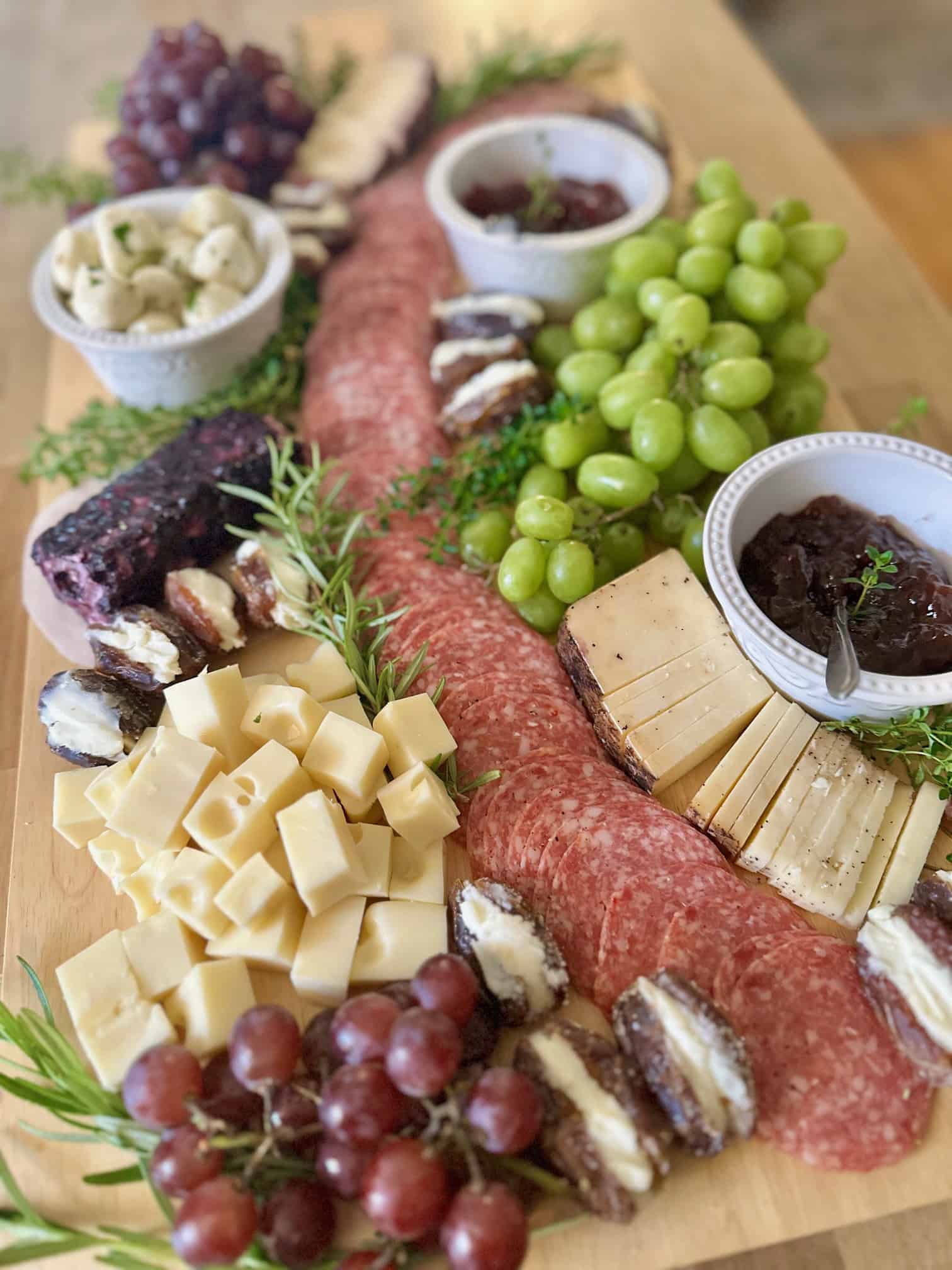 A large paddle board for charcuterie with meats, cheeses and fruit on it. 