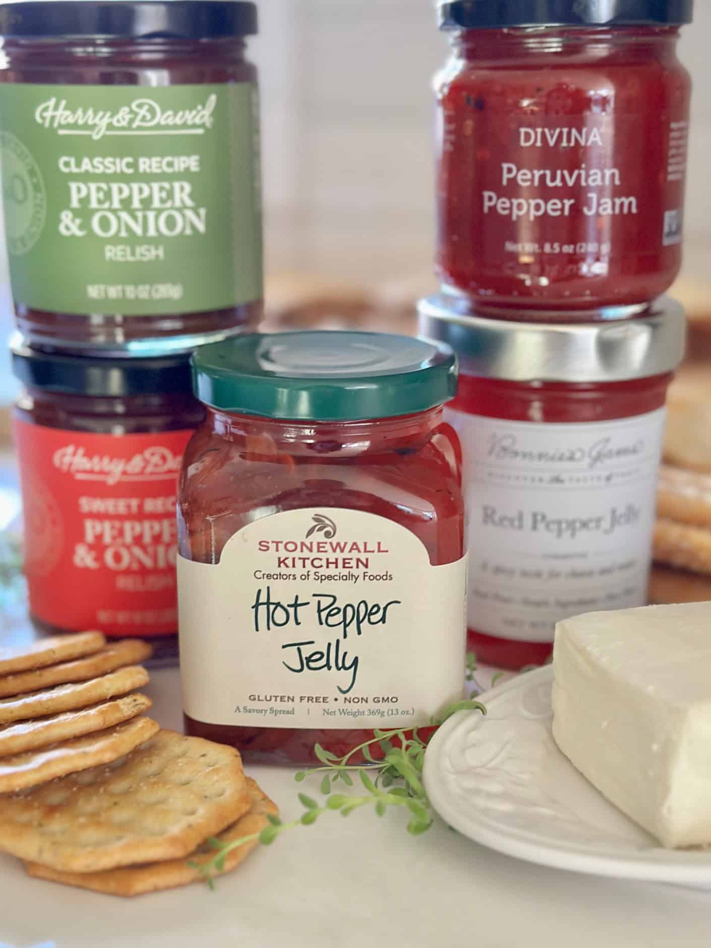 An assortment of pepper jelly with a block of cream cheese. 