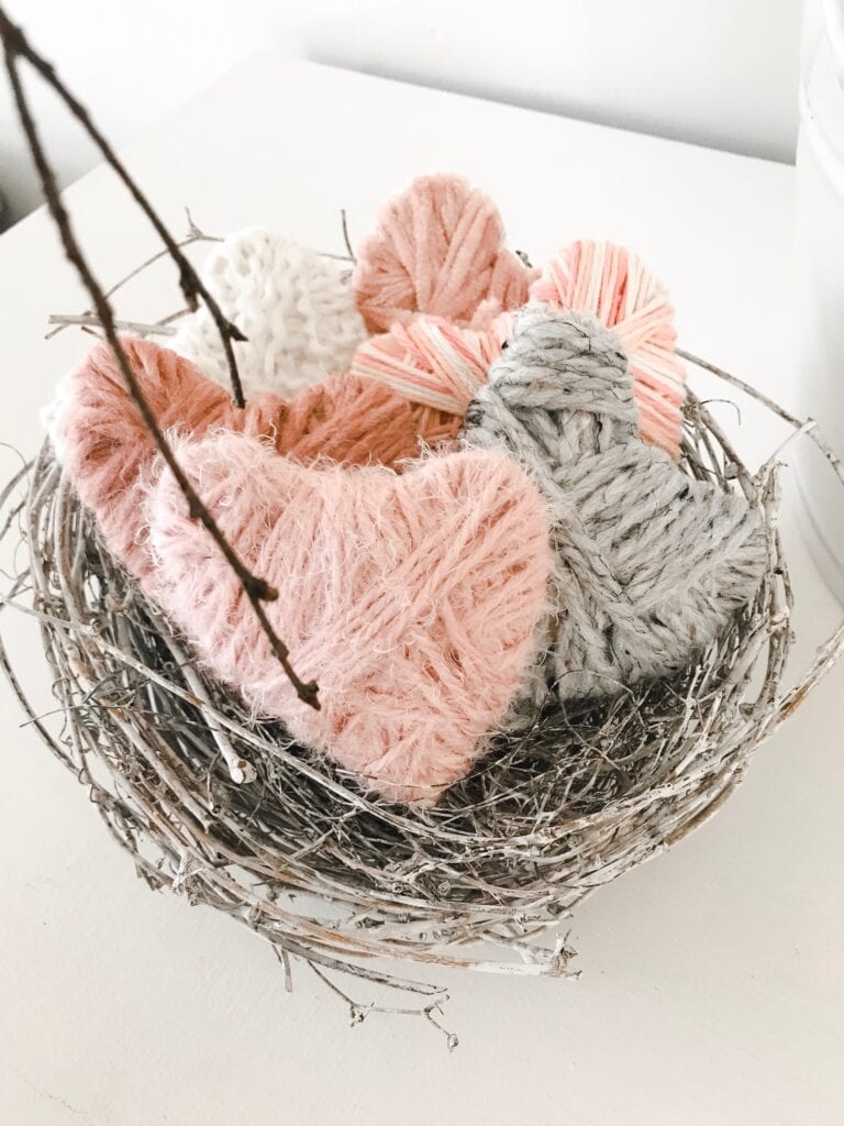 Yarn wrapped hearts in a whitewashed birds nest. 