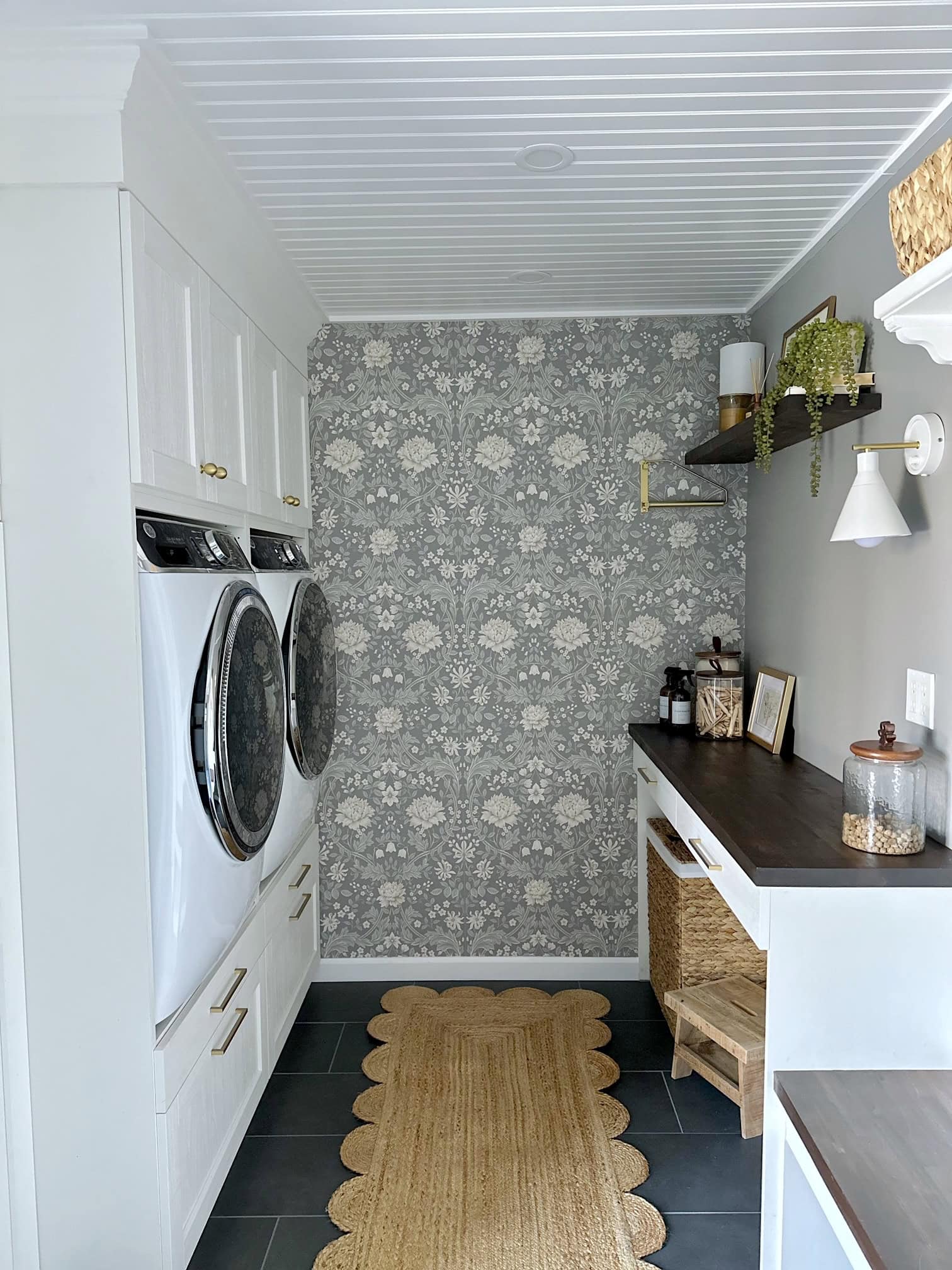 A view of our galley style laundry room with a wall of cabinets on the left, folding counter and dog walking station on the right. 