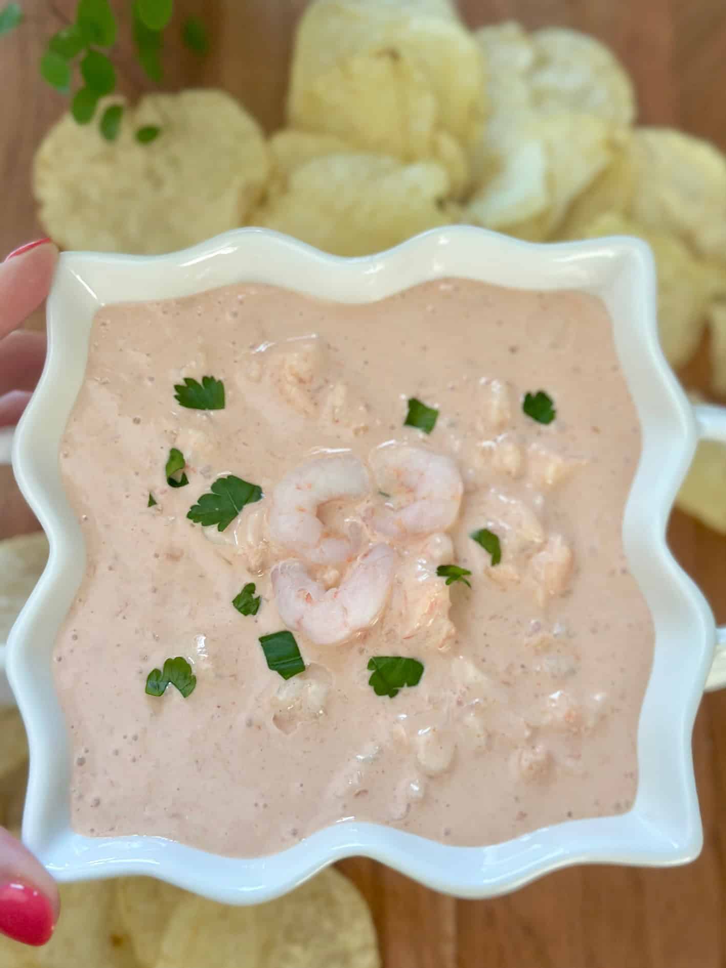 A pretty scallop edge bowl with Shrimp Cocktail Dip. Chips are laying in the background.