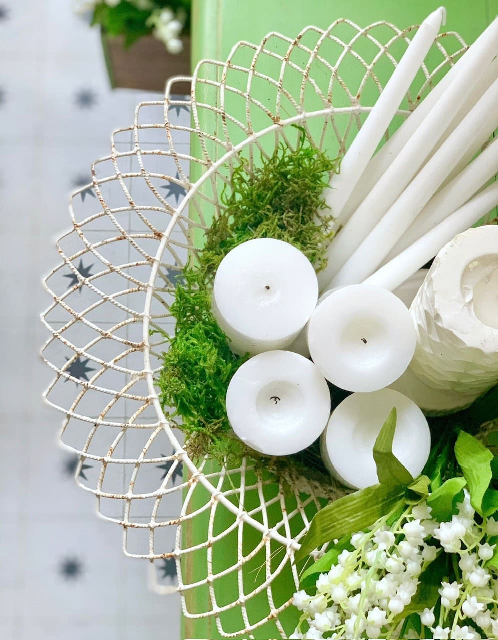Vintage white wire basket with white candles, moss and faux flowers. 