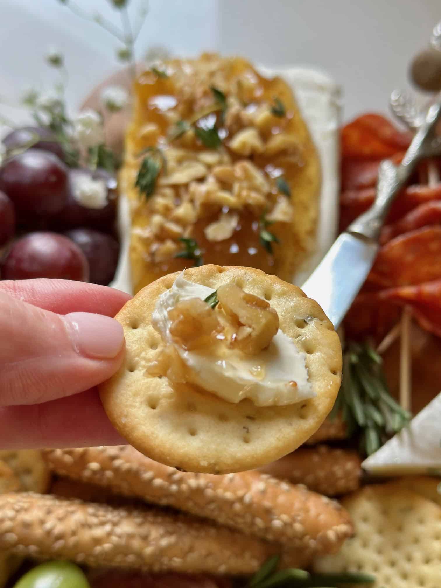 Cream cheese on a charcuterie board with a serving on a cracker. 