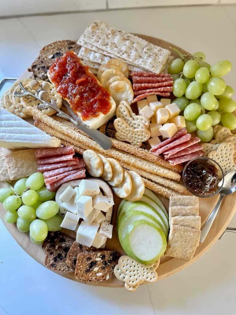 A charcuterie board filled with crackers with jam, and cheese. 
