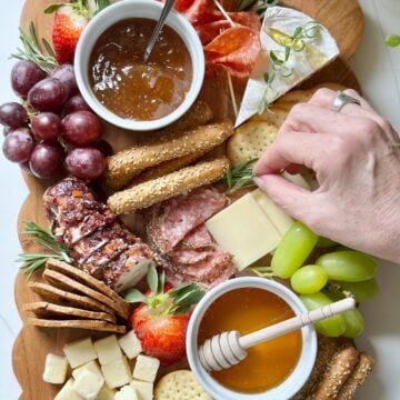 Placing herb garnish on a charcuterie board.