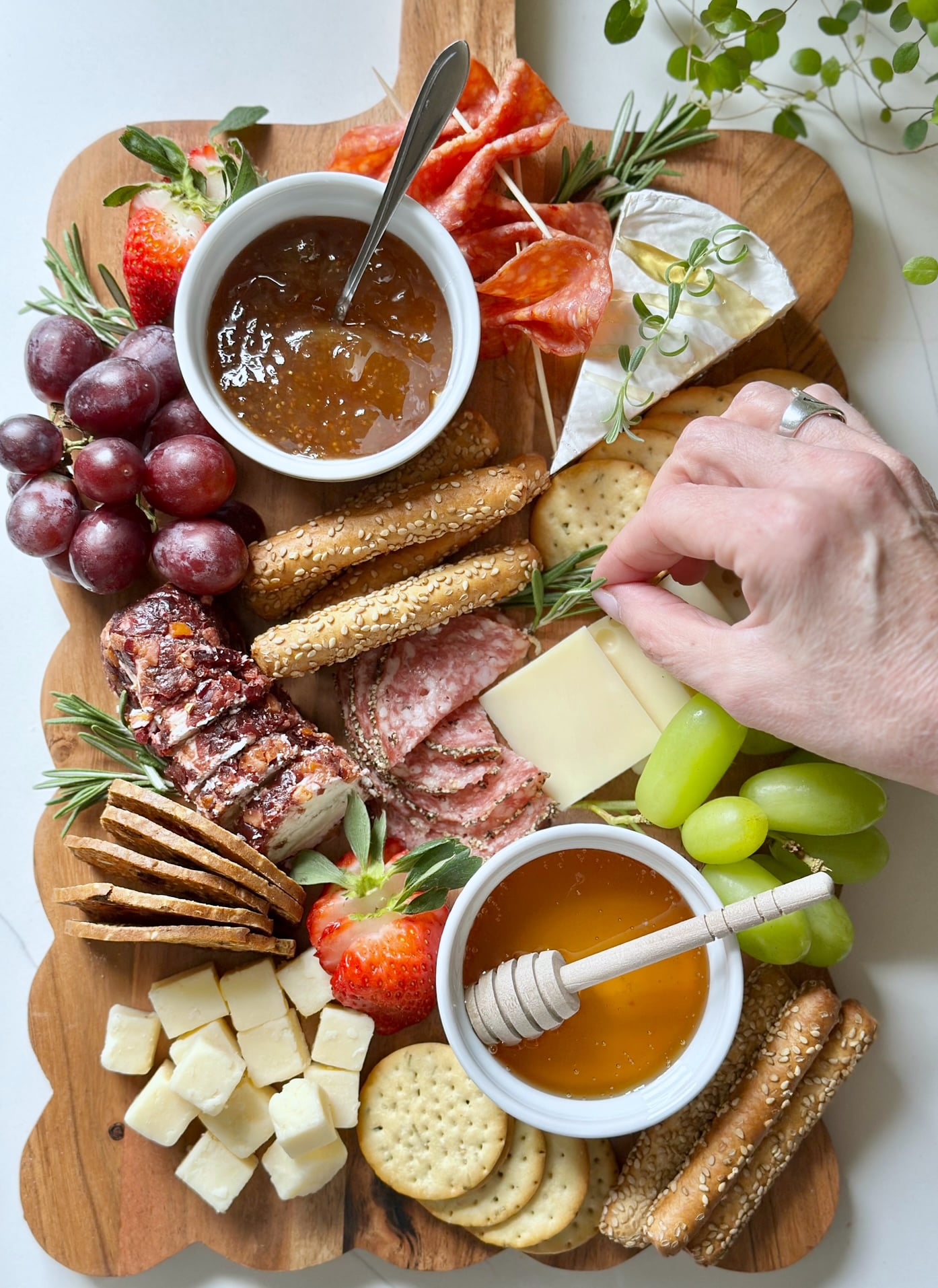 Placing herb garnish on a charcuterie board.