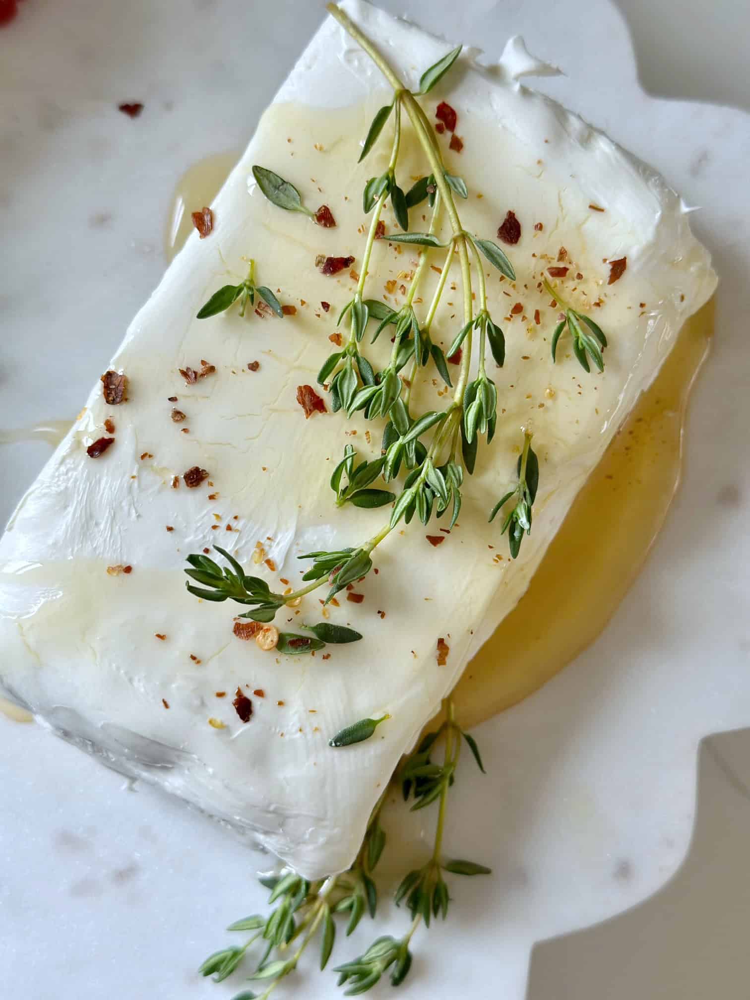Cream cheese with hot honey and thyme garnish. 