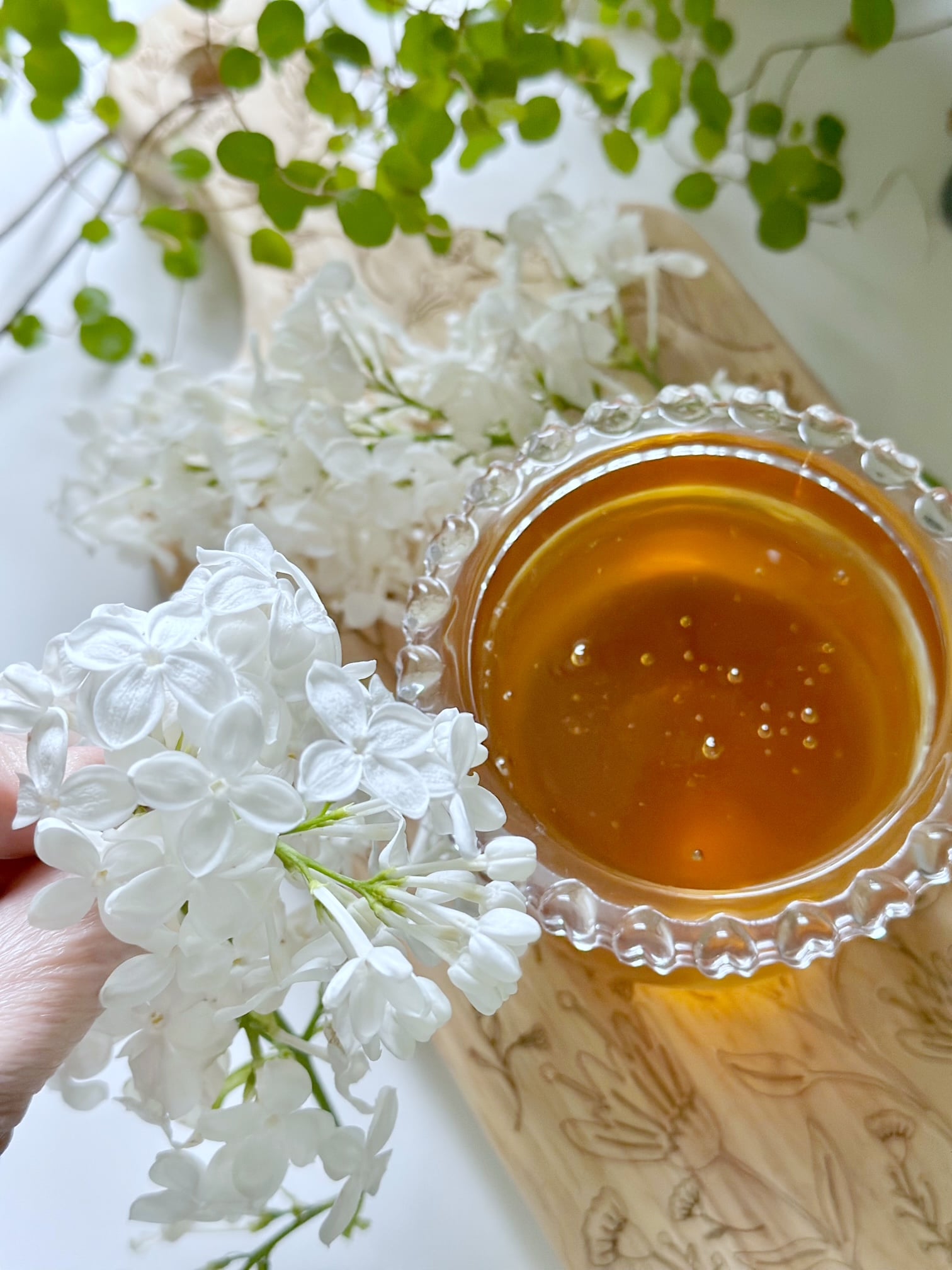 Holding cluster of white lilac with a bowl of honey. 