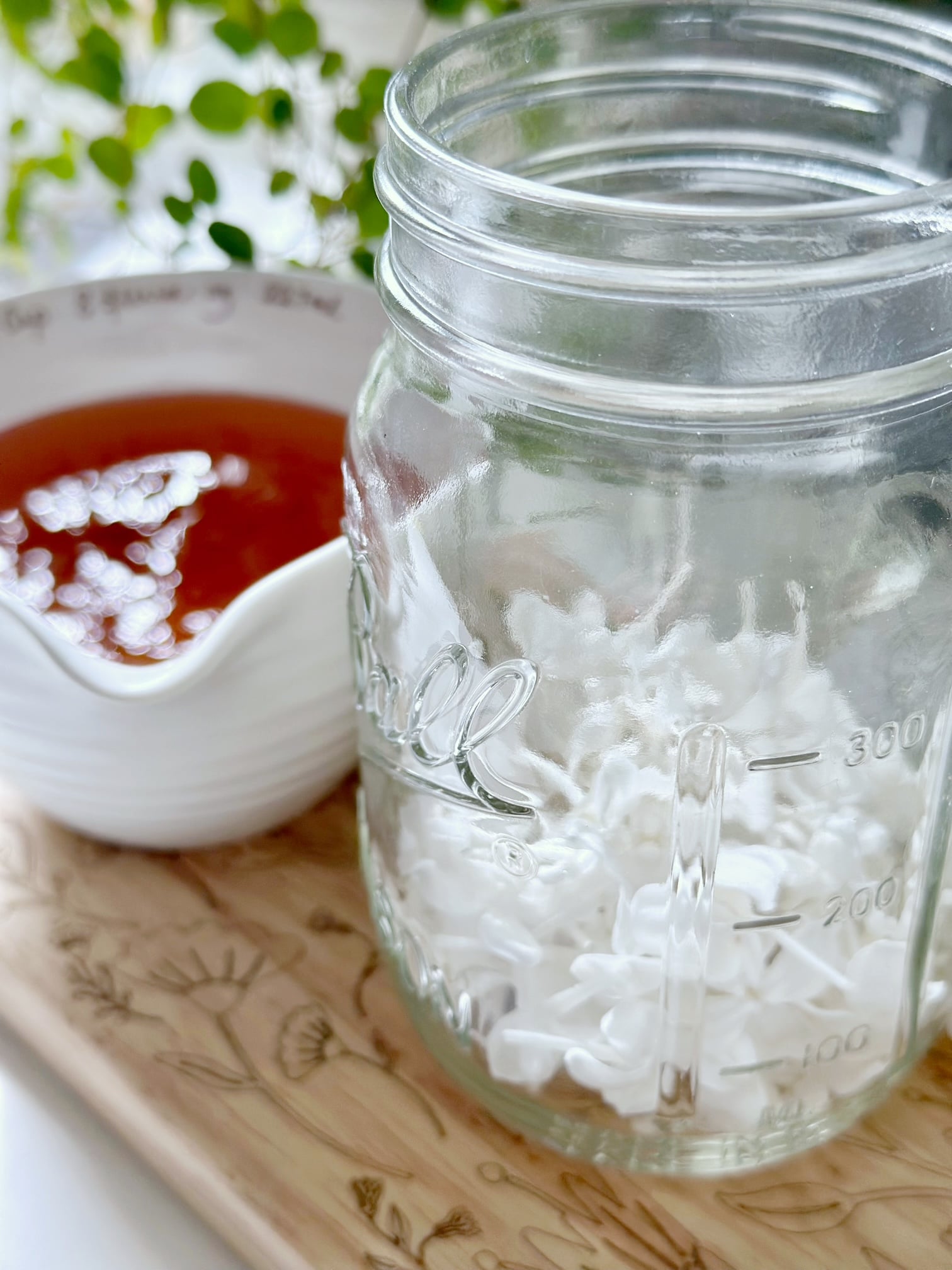 White lavender flowers in a ball jar with honey nearby.
