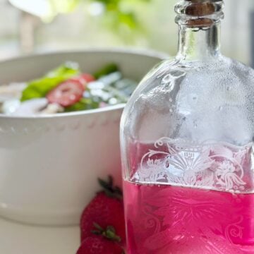 Chive blossom vinegar in front of a salad.